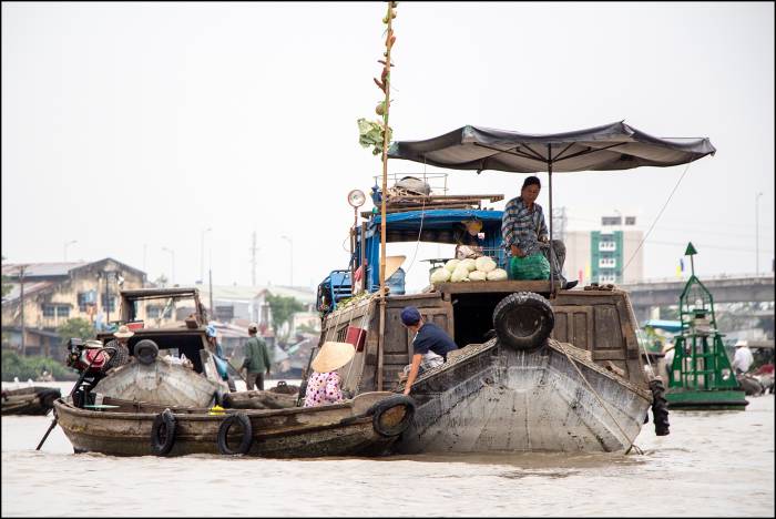 smaller canoes dock by the large barges that have a variety of fresh produce on offer Cai Rang floating market